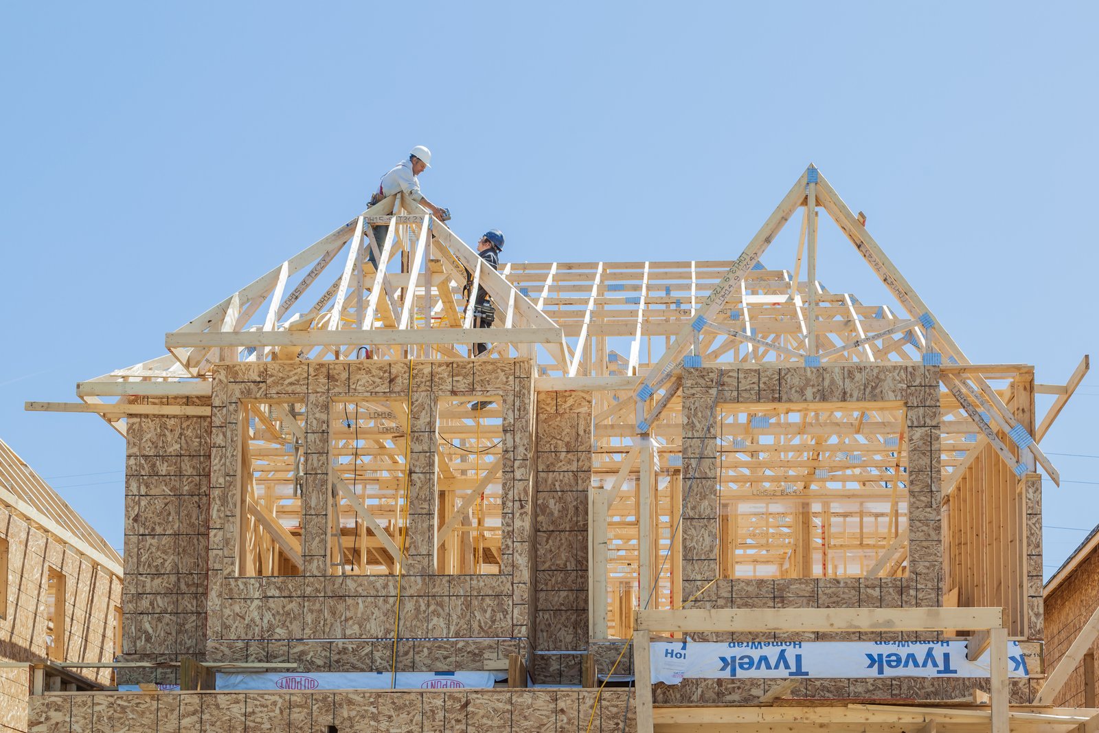 Toronto, Canada - May 10 2017: New house under construction, two workers installing roof truss.